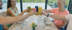 Group of people toasting smoothies over a white table