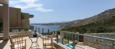 Furnished terrace overlooking the stone walls and swimming pool below, and the hills and Aegean Sea in the background