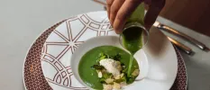 White plate with rice and broccoli in a green sauce, as a staff members pours more on