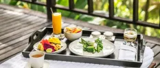Tray with orange juice, a plate of fruit, a plate of green vegetables and a cup of herbal tea