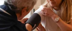 Medical professional taking the blood pressure of a woman with blonde hair