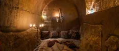 Stone cave with patterned carpet and cushions lit by candlelight 