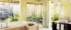 Luxury bohemian-style bathroom with full-length windows, a marble bathtub and black vanity unit