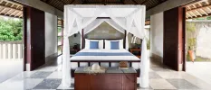 Bedroom with dark-wood sliding doors, beamed ceilings and a four-poster bed draped in sheer white fabric