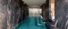 Indoor pool with dark grey marble-like walls and lanterns to one side