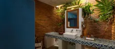 Stone-walled bathroom with a tiled vanity, palm trees and a wooden mirror