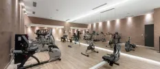 Gym with a wall of full-length mirrors, a rowing machine, bikes and treadmills