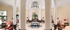 Airy lobby area with cream walls and white pillars, a black pendant light, terracotta chairs and cream sofas