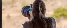 Woman with long hair in a clip takes pictures with a large professional camera in the African wilderness