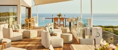 Sea-facing rooftop with wooden decking, neutral plush seating and wooden stalls