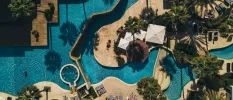 Lagoon-like pools seen from the air in landscaped grounds peppered with palm trees