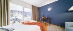 Dark blue wall, neutral curtains and white bedding and a terracotta throw