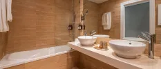 Modern bathroom with caramel-coloured walls, a large vanity unit with his and hers sinks and a frosted window
