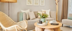 Smart hotel room living area with neutral seating and cushions, a rattan chair and neutral artwork