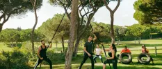 Group during a fitness class using ropes, tyres and weights - taking place in a leafy garden