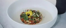 White bowl filled with healthy looking veg and grains, garnished with an edible yellow pansy