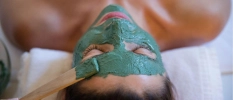A lady with green mud on her face having a facial done