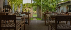 Indoor ourdoor view of the restaurant with tables and chairs with garden at the back 