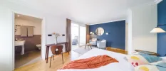 Hotel room with blue and white walls, white bedding and a terracotta throw