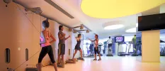 People work out using weighted ropes and treadmills in an airy gym studio