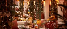 Restaurant with fairy lights, terracotta cushions and table lanterns, plus climbing greenery