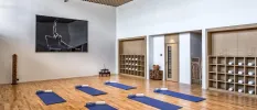 Airy indoor studio with white walls and blue mats lined up in two rows and a white towel on each