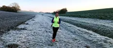 Lady jogging in a snowy field wearing a high-vis vest