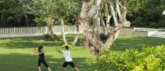 Two people in active wear doing Tai Chi in a tropical garden setting