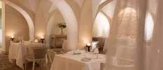 Romantic restaurant with curved white walls, sheer white curtains, crisp white tablecloths and lantern and candlelight