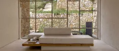 Modern beige sofa with rectangular cushions in front of a floor-to-ceiling window overlooking nature