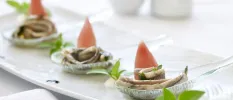 White platter with three stacks of seafood, piled up in shells with sprigs of mint
