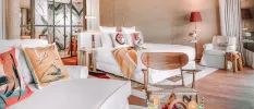 White daybeds with bohemian printed cushions, a wooden stall and seating and a basket of fruit