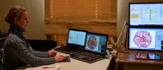 A healthcare professional surrounded by screens showing scans as she sits at a desk