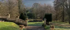 Grand concrete wall and stone pathway lined with lawns and leafy trees