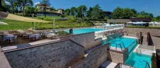 Swimming pools cascaded over mutliple levels, set in stone walled terraces and overlooked by landscaped gardens