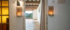 Entrance to a large light-filled room with a window overlooking green hills, with candles in scripture holders either side