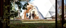 Group of people stand outside a domed white structure in a garden