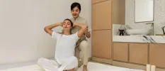 Woman in white leans back as a therapist pulls her arms backgrounds during a spa treatment