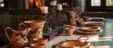 Wooden table laid up with terracotta pouring jugs, plates and cups and an intricate candleabra