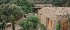 Traditional stone building surrounded by trees, and tables with white tablecloths set up for dining 