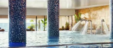 Indoor pool with blue tiled pillars and high-pressure water jets in a room with huge windows and sea views