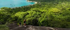 Couple in black tops and denim shorts hiking up a dark rockface 