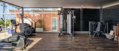 Gym with dark-wood floors, treadmills, bikes and a stepper with floor-to-ceiling windows