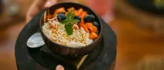 Waiter carrying a black poke bowl topped with a sprig of mint
