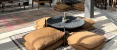 Brown square floor cushions around a round low table on a patterned rug