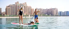 Smiling family paddle board in the sea in front of Fairmont The Palm