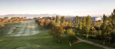 Golf greens surrounded by trees and mountains