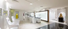 Elegant white spa area with glossy tiled floor, a gold Buddha statue and a white reception desk