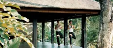 Man and woman in a yoga pose in an outdoor pavilion in the jungle