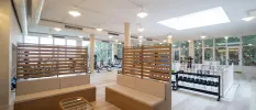 Brightly lit gym with treadmills, bikes and weights, plus a wooden seating area with white cushions
